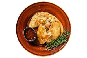 Fried empanadas with minced beef meat served on a plate with chili sauce. Isolated on white background. photo