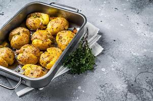 Broken potatoes baked with rosemary and thyme. Gray background. Top view. Copy space photo