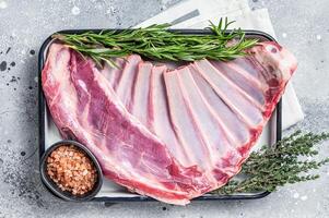 Ready for cooking Rack of lamb, raw mutton ribs with herbs. Gray background. Top view photo