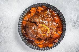 Braised meat on the bone Osso Buco in tomato sauce, veal italian meat Ossobuco. White background. Top view. Copy space photo