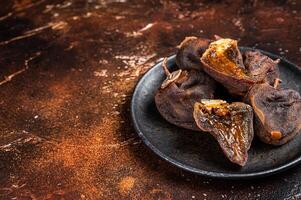 Dried persimmon fruit on a plate. Dark background. Top view. Copy space photo