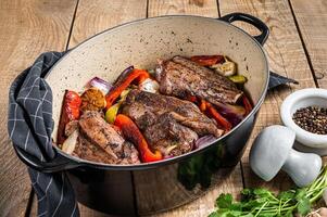 Roasted slow cooked lamb shanks with vegetables and herbs. Wooden background. Top view photo