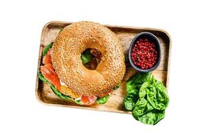 Healthy freshly baked bagel filled with smoked salmon, spinach and egg. Isolated on white background. Top view. photo