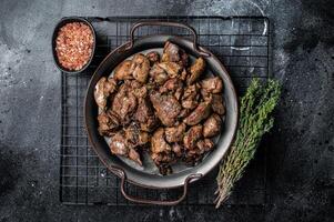 Fried chicken liver with onions and herbs. Black background. Top view photo
