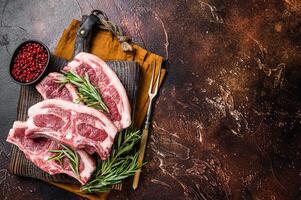Raw fresh saddle of lamb mutton with herbs and spices on butcher board. Dark background. Top view. Copy space photo
