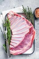 Ready for cooking Rack of lamb, raw mutton ribs with herbs. Gray background. Top view photo
