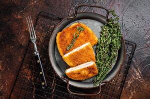 Cordon bleu chicken fillet cutlet with ham and cheese. Dark background. Top view photo