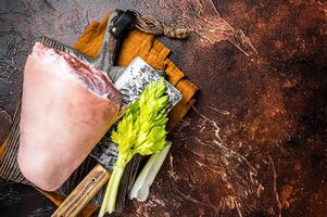 Fresh Raw pork shank knuckle on a butcher board with herbs for cooking. Dark background. Top view. Copy space photo