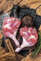 Raw duck legs with spices and chef cleaver on a wooden board. Wooden background. Top view photo