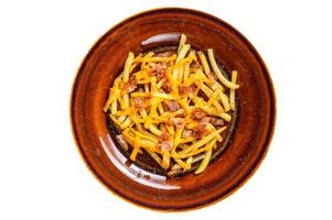 French fries with melted cheddar cheese and bacon served in a rustic plate. Isolated on white background. photo
