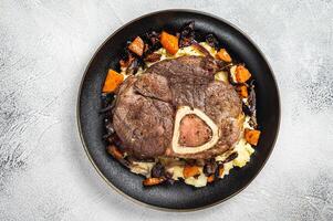 Osso buco cross cut veal shank with mashed potato on a plate. White background. Top view. Copy space photo
