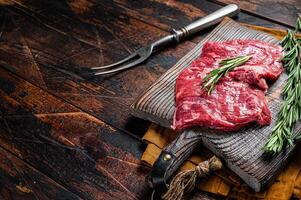 Raw alternative skirt beef steak on butcher board. Wooden background. Top view. Copy space photo
