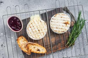 Grilled Camembert cheese on grill with cranberry sauce and toast. Gray background. Top view photo