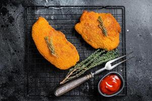Fried Breaded weiner schnitzel, cooked meat steak. Black background. Top view photo