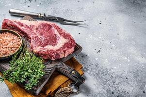 Raw uncooked black angus beef cowboy or rib eye steak. Gray background. Top view. Copy space photo