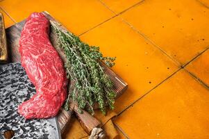 Fresh Raw Machete beef meat steak or hanging tender cut on butcher cutting board. Orange background. Top view. Copy space photo