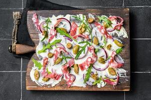 Butterboard, Butter Board with olives, onion, arugula, capers and tomato. Black background. Top view photo