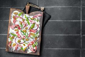 Butterboard, Butter Board with olives, onion, arugula, capers and tomato. Black background. Top view. Copy space photo