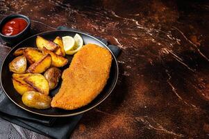 Roast pork schnitzel with fried potato, cooked meat steak. Dark background. Top view. Copy space photo