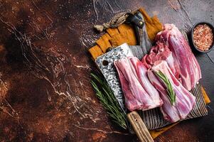 Uncooked Raw lamb mutton shanks on a butcher board. Dark background. Top view. Copy space photo