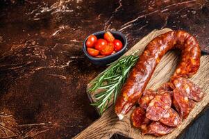Dry cured Spanish Chorizo sausage, slices of meat with herbs and spices. Dark background. Top view. Copy space photo