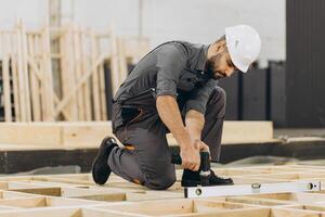 Construction worker building wooden frame using level tool and drill photo