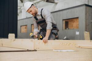 Carpenter using cordless drill assembling wooden frame for modular building photo