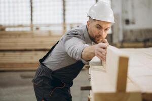 Carpenter working with wood beams in a factory for modular building photo