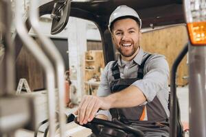 Smiling engineer driving forklift in modular building factory photo