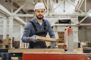 Carpenter working with wood plank in a factory for modular building photo