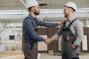Construction workers shaking hands in modular building factory photo