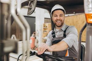 Smiling engineer driving forklift in modular building factory photo