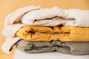 Stack of warm padded jackets on a white surface photo