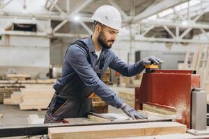 Carpenter operating woodworking machine in factory for modular building photo
