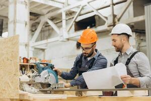 Builders working with circular saw and blueprint in workshop photo