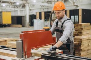 Carpenter working with wood plank and precision saw in workshop for modular building industry photo