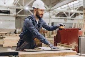 Carpenter operating woodworking machine in factory for modular building photo