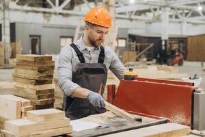 Carpenter working with wood plank and saw in a factory for modular building photo