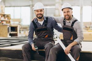 Construction workers smiling and posing in modular building factory photo