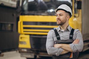 Engineer wearing hardhat and overalls standing with arms crossed in front of truck in modular building factory photo