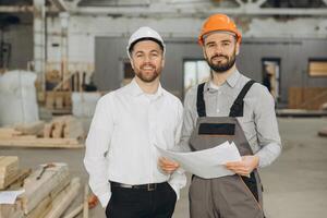 Architect and construction worker discussing plans in modular building factory photo