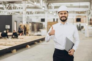 Smiling engineer gesturing thumbs up in modular building factory photo