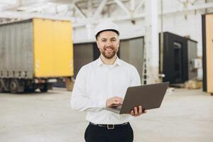 Smiling engineer using laptop in modular building factory photo
