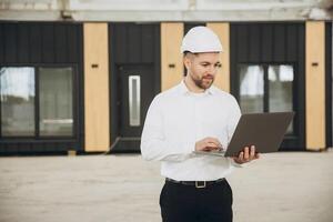 Architect using laptop in front of modular building photo