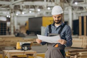 Construction worker reading blueprint in modular building factory photo