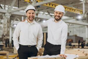Smiling engineers discussing plans in modular building factory photo