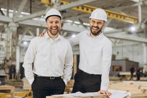 Engineers smiling and leaning on wood in modular building factory photo