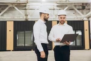 Engineers using laptop in modular building factory photo