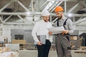 Engineers discussing blueprint in modular building factory photo