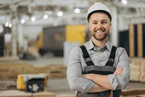 Smiling engineer posing with crossed arms in modular building factory photo